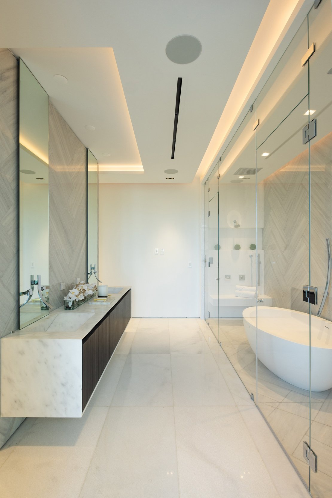 Luxury interior from the Armonia Materica collection featuring a white marble vanity, a freestanding soaking tub, and custom vertical wood-clad pillars.