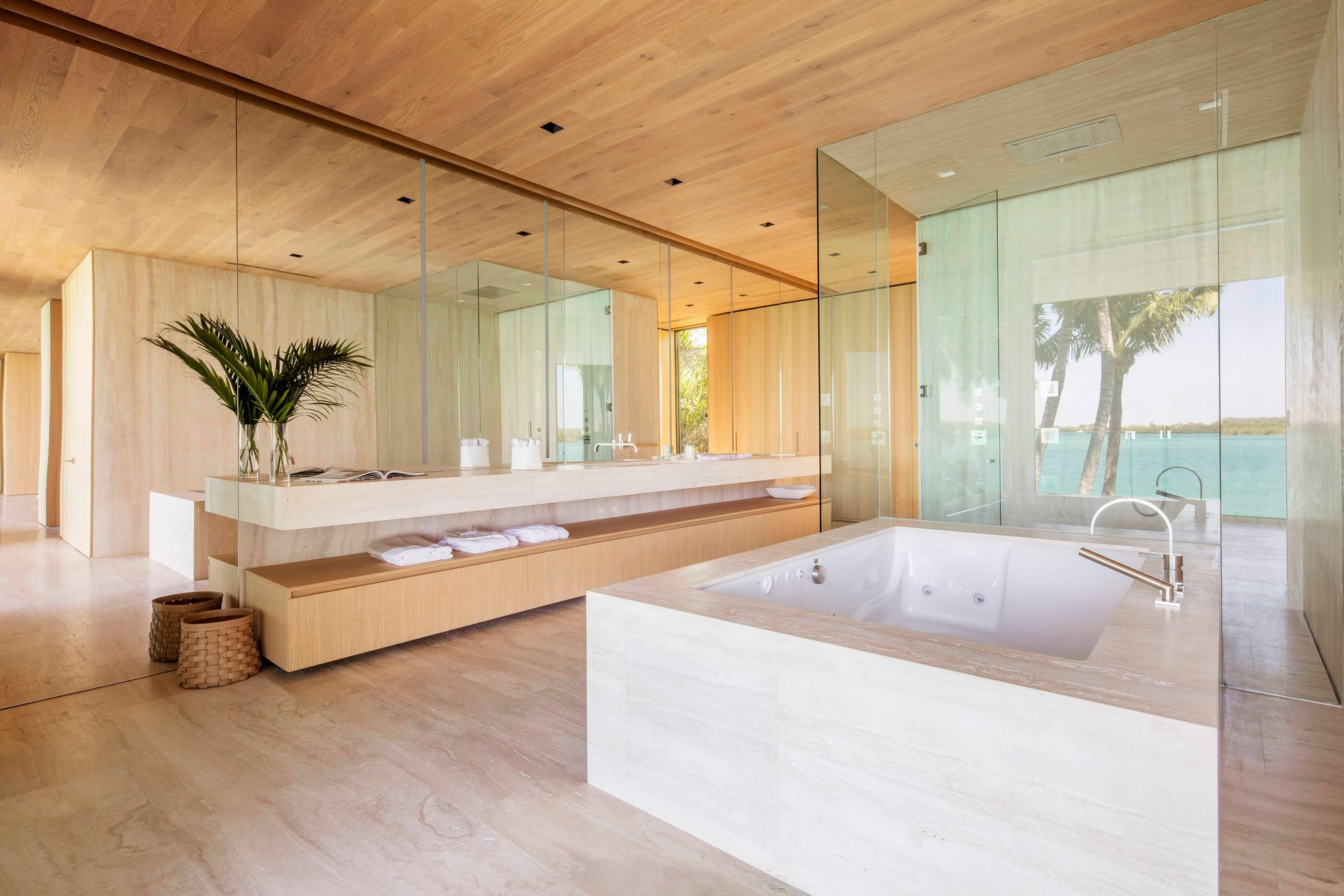 Custom travertine stone master bathtub, matching double vanity with wood drawers, and extensive wood paneling.