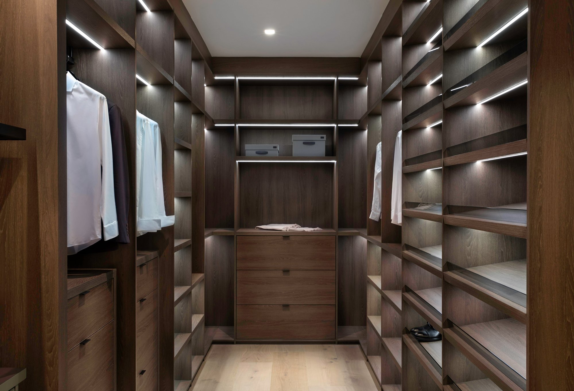 Walk-in closet with dark wood cabinetry, symmetrical open shelving, and integrated LED lighting.