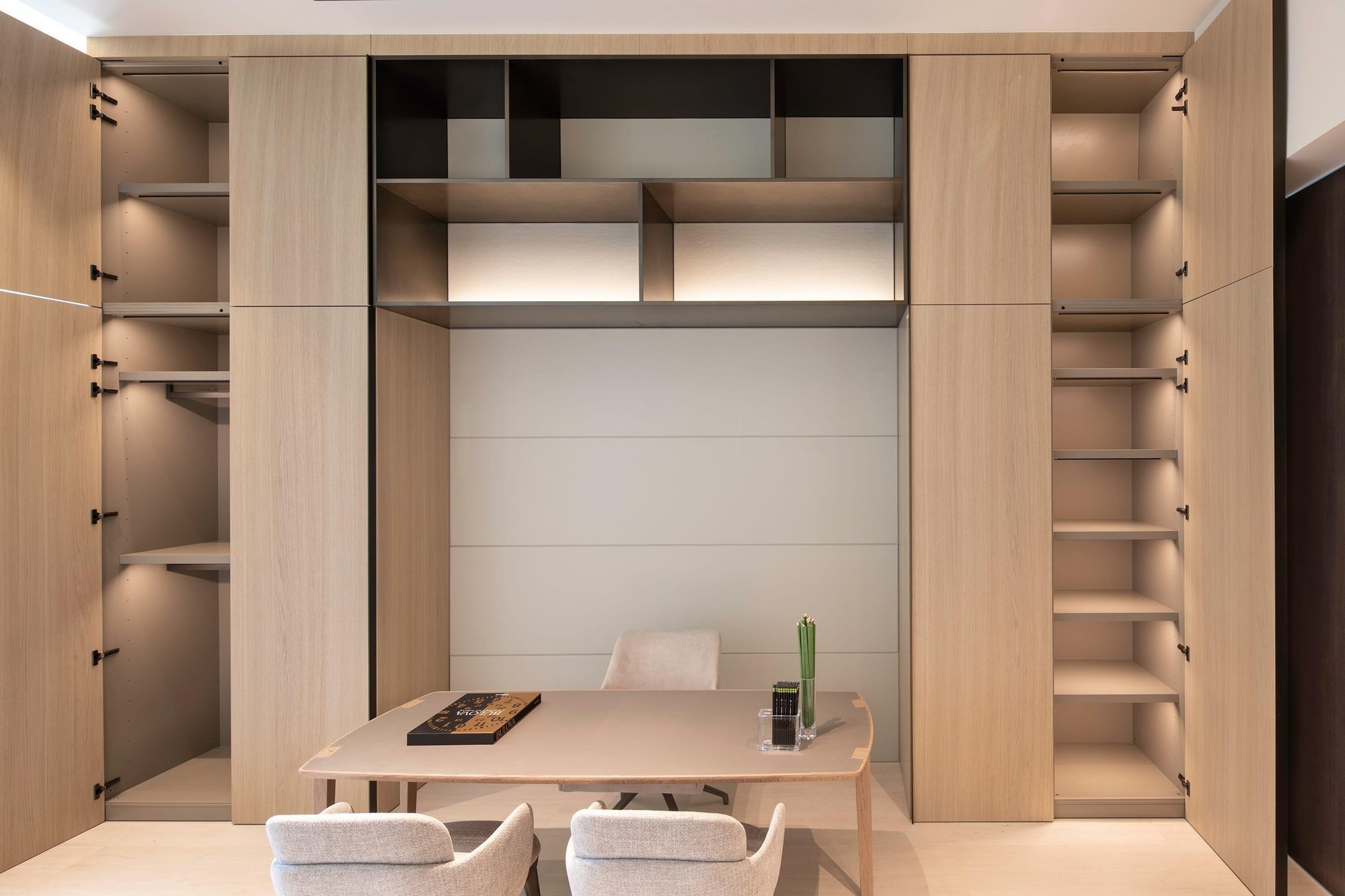 Integrated home office with light wood cabinetry, open shelving, and a modern executive desk.