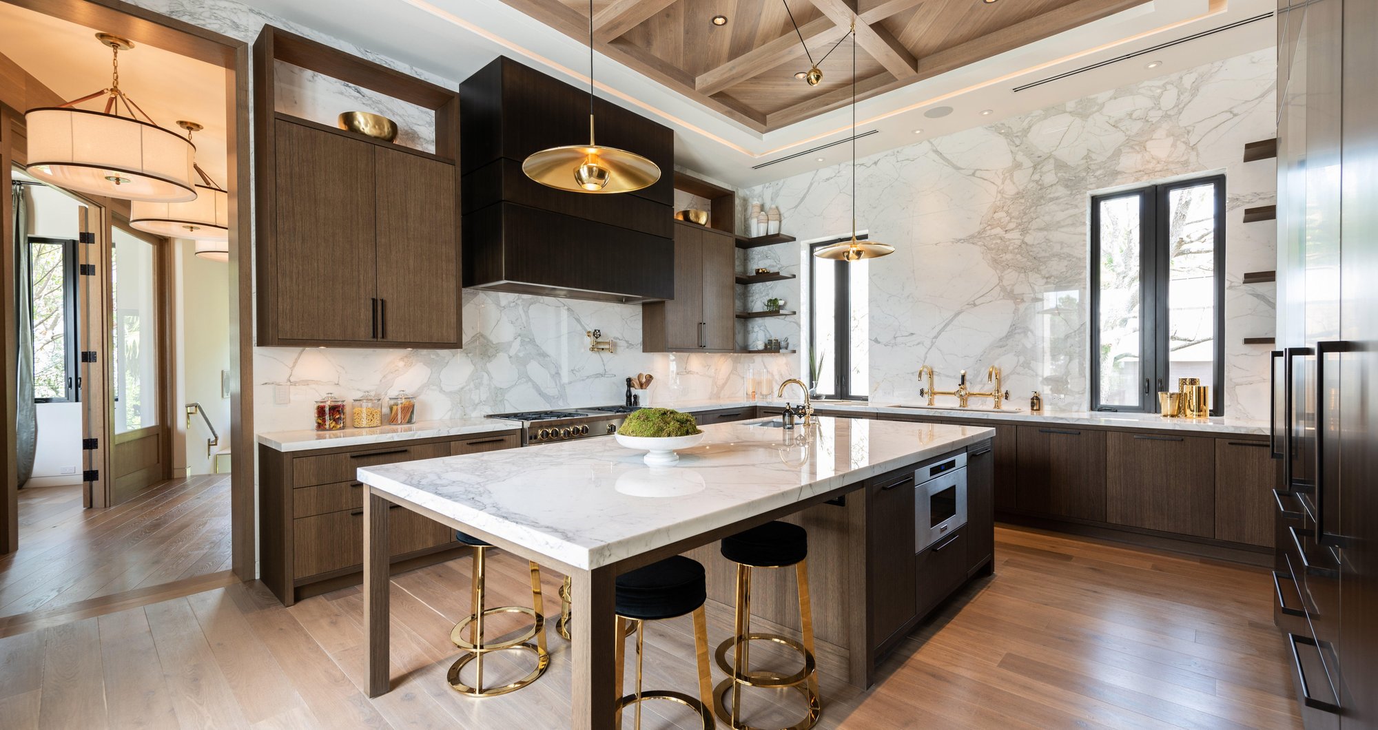Modern Italian kitchen and living space with white marble island and custom cabinetry.